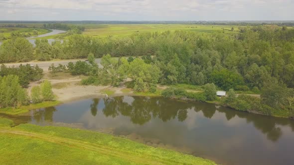 Newlywed Couple on Green Bank of Calm Lake Aerial View