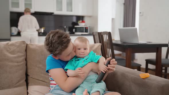 Two Brothers Playing on Sofa While Mother Cooking Dinner