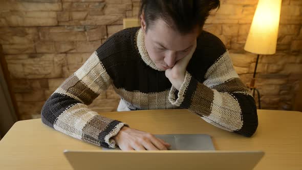 Stressed Young Man Looking Sad and Lonely While Using Laptop at Home