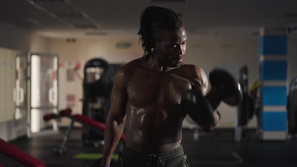 Front View Concentrated Sportsman Lifting Heavy Dumbbells Perspiring in Gym Indoors