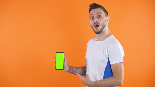 Soccer Fan In White Blue Shirt Show Green Screen Smartphone Orange Background 