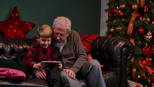 Elegant Old Man and Little Boy Talking on Video Communication on Tablet