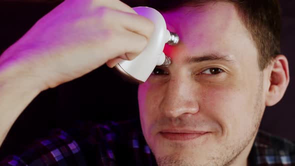 Young Man Using 3d Massager for Face