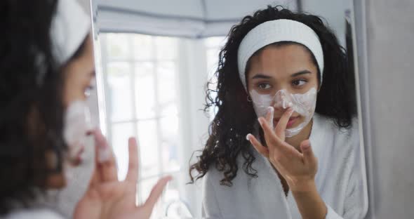 Mixed race woman applying face cream in bathroom