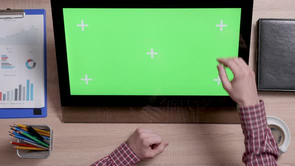 Top View of Man's Hands Scrolling Over the Left Edge of a Green Screen Touch Monitor