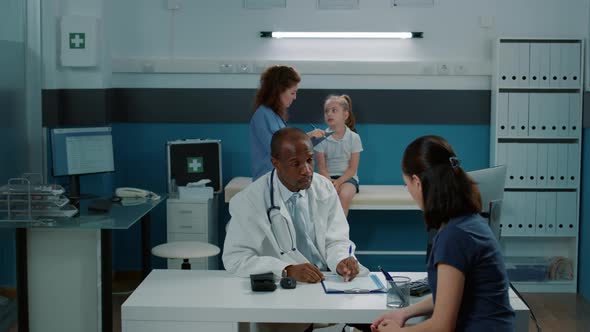 Physician Having Conversation with Adult in Medical Cabinet