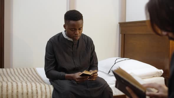 African American Young Catholic Priest Reads the Bible at His Room Seminarist is Reading a Book