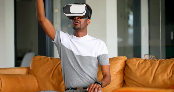 Male executive using virtual reality headset on sofa