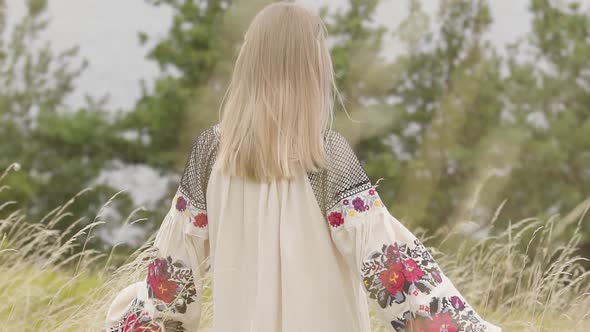 Rear View at Cute Caucasian Woman Wearing Long Summer Fashion Dress Standing on the Field