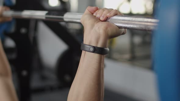 Close-up of a man holding his hands with a barbell for pulling, squatting, fitness in the gym. Sport