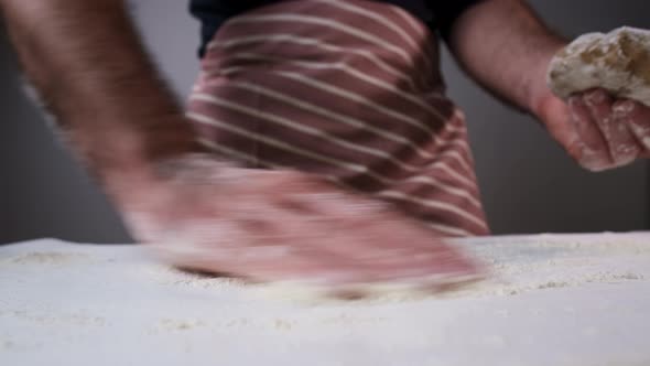 Man Baker Distributes Flour and Puts Raw Dough on Table