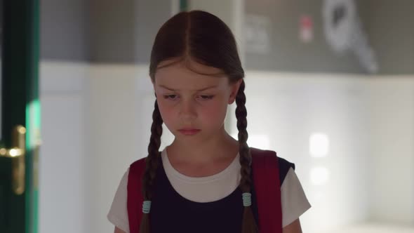 Slider Shot of Cute Upset Preteen Girl with Backpack Walking in Empty School Corridor