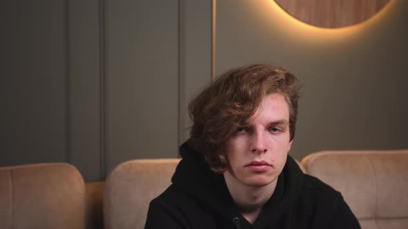 Handsome Serious Caucasian Man Looking at Camera Sitting on Couch at Home