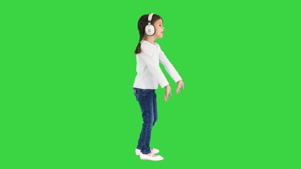 Excited Little Girl Dressed in White Listening To the Music in Headphones and Singing Along on a