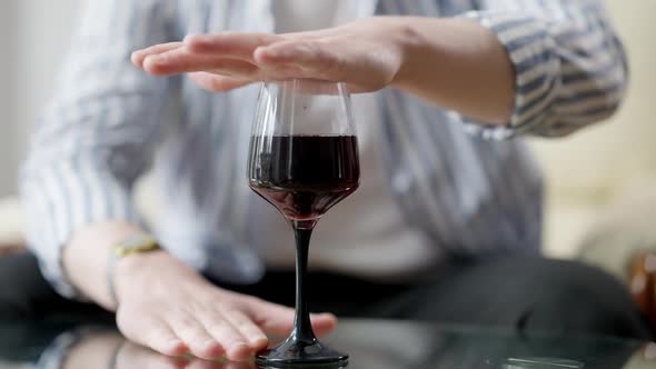 Male Hand Covering Glass with Red Wine Standing on Glass Table