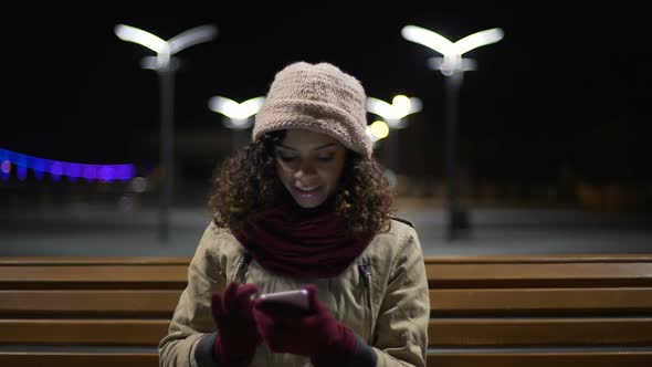 Biracial Girl Sitting Outdoors, Watching Funny Images and Sincerely Smiling