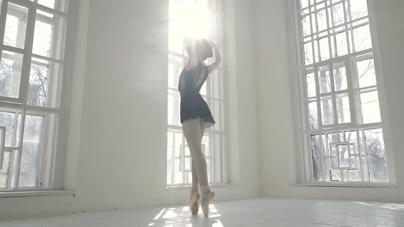 Young ballerina standing near the window. 