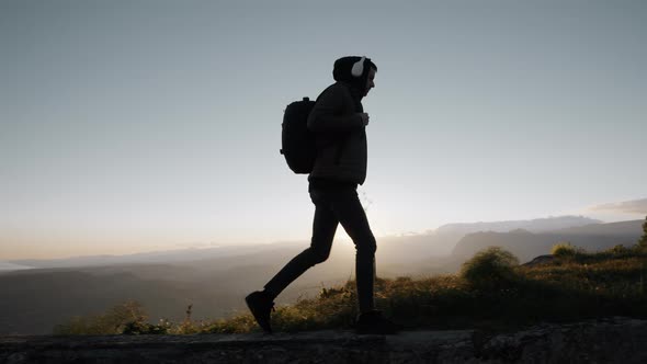 Silhouette of hiker in the mountains walking with backpack