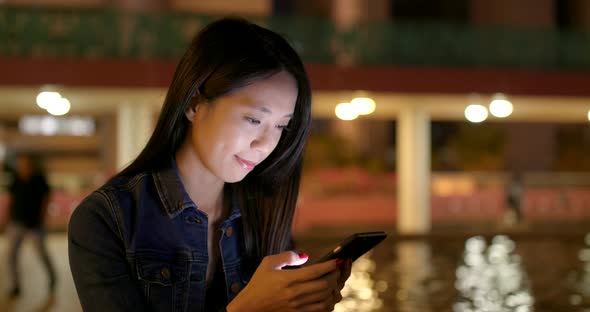 Woman use of mobile phone for online at night in the city