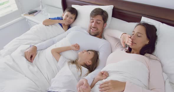 Family relaxing together on bed in bedroom at home 4k