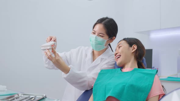 Asian young girl listen woman dentist explain about oral care and teeth brushing for brace in clinic