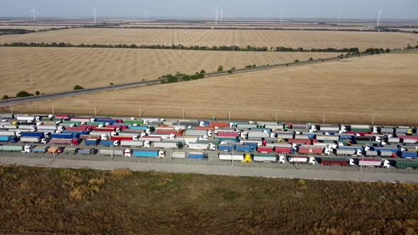 Trucks with trailers stand in a long queue at the port terminal for unloading grain