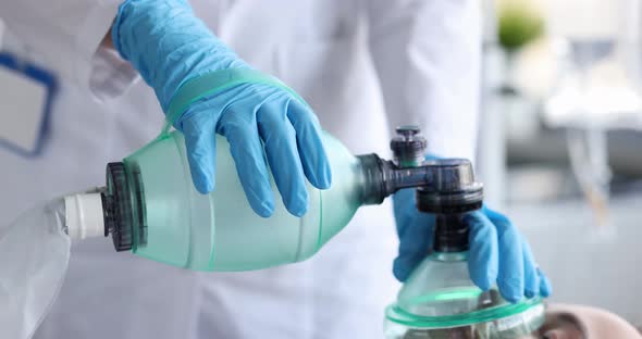 Doctor Puts on Oxygen Mask on Motionless Patient Closeup