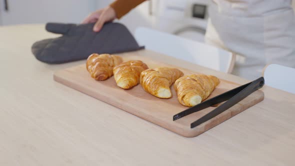 Attractive young female Latino baking croissant on table in kitchen. Activity homemade in house.