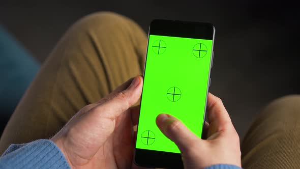 Man Using Smartphone with Green Mockup Screen in Vertical Mode