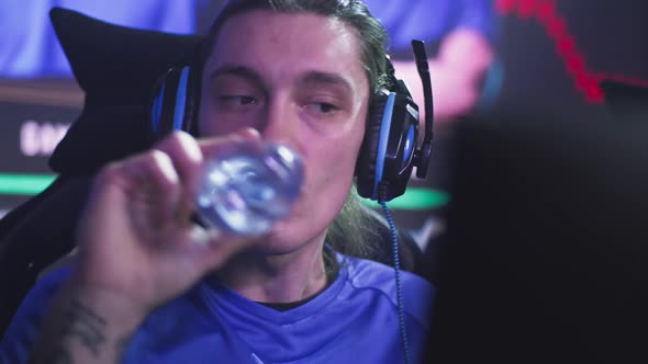 Young Gamer with Bottle Watching Replay During Tournament