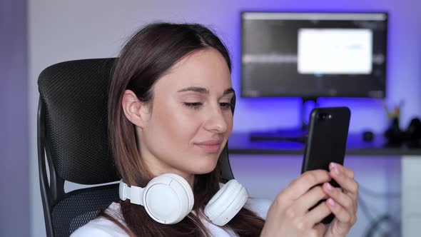 Young Woman Using Mobile Phone with Headphone at Home