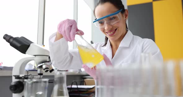 Smiling Scientist Holding Flask with Yellow Liquid in Laboratory