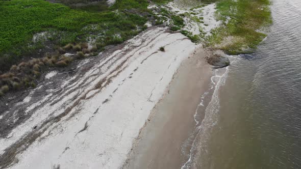 white sand beach vegitation waves washing ashore tybee island georgia aerial drone