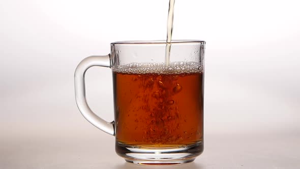 Glass Cup Is Poured Hot Black Tea. Slow Motion, Closeups