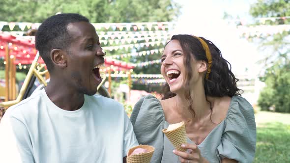 Happy Multiracial Couple Have Fun with Ice Cream in Park