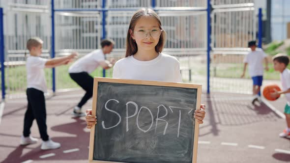 Portrait of Asian Girl Standing at Basketball Court with Schoolboard in Hands Text Sport During