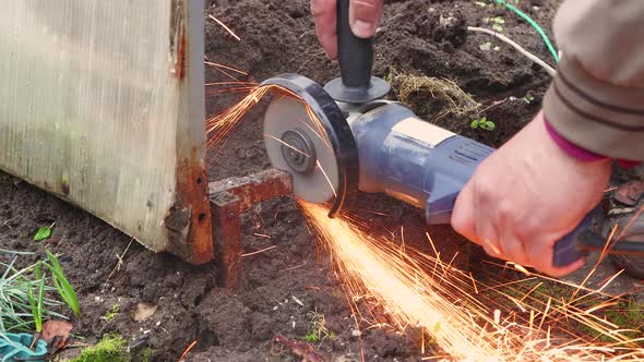 Male Hands are Cutting Rusty Metalwork with an Angle Grinder