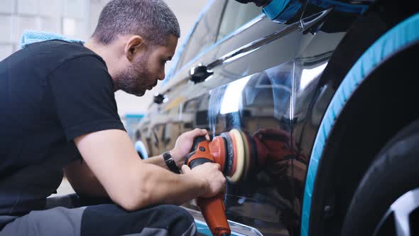 An Experienced Detailing Studio Worker Polishing a Car