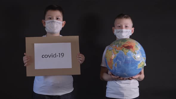 Boy Holds a Globe, a Model of the Planet Earth. Child Is Holding a Sign with the Inscription: COVID