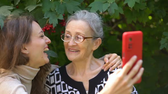 Adult Daughter and Senior Mum are Taking Selfportrait Picture Selfie on Red Smartphone Together