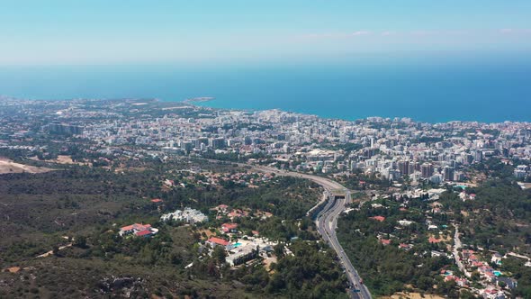 Flying above a highway looking over the sprawling city towards the Mediterranean