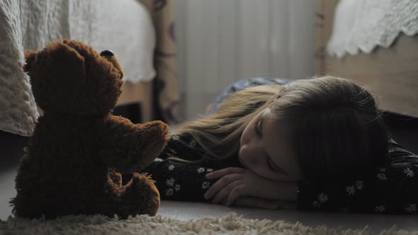 Depressed Little Girl and Her Best Friend Teddy Bear in the Dark Gloomy Room of His House