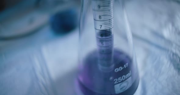 Scientist taking out a purple liquid from a conical flask in a lab,tracking shot