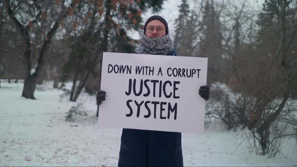 A man is holding a sign Down with a corrupt justice system. Single Protest.