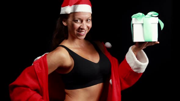 Smiling muscular woman with giftposing in santa outfit