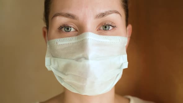 young woman in a protective medical mask, she looks directly at the camera