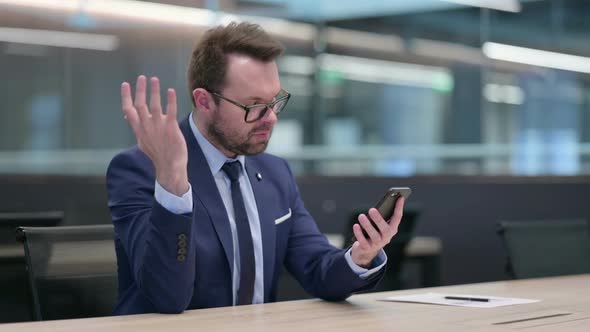Middle Aged Businessman Reacting to Loss on Smartphone
