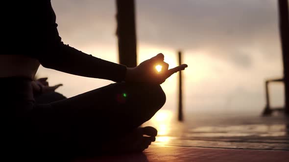 Silhouette of Unrecognizable Yogi Girl Sitting in Lotus Pose in Front the Sea in Summer on Sunset