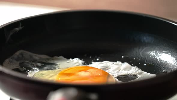 the Process of Making Scrambled Eggs From One Egg in a Black Frying Pan