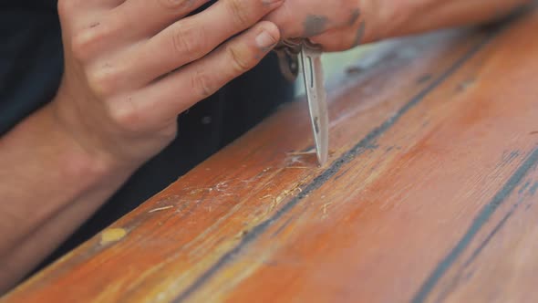 Using knife to cut damaged timber from wooden boat cabin  planking. Handheld, CLOSE UP.